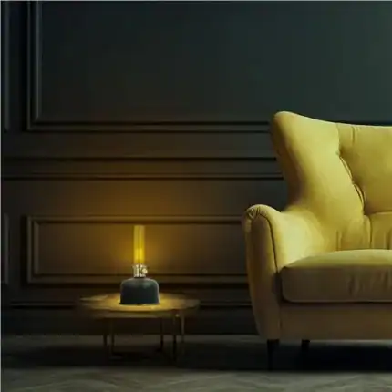 Lámpara de mesa moderna con luz cálida junto a sillón amarillo en sala elegante.